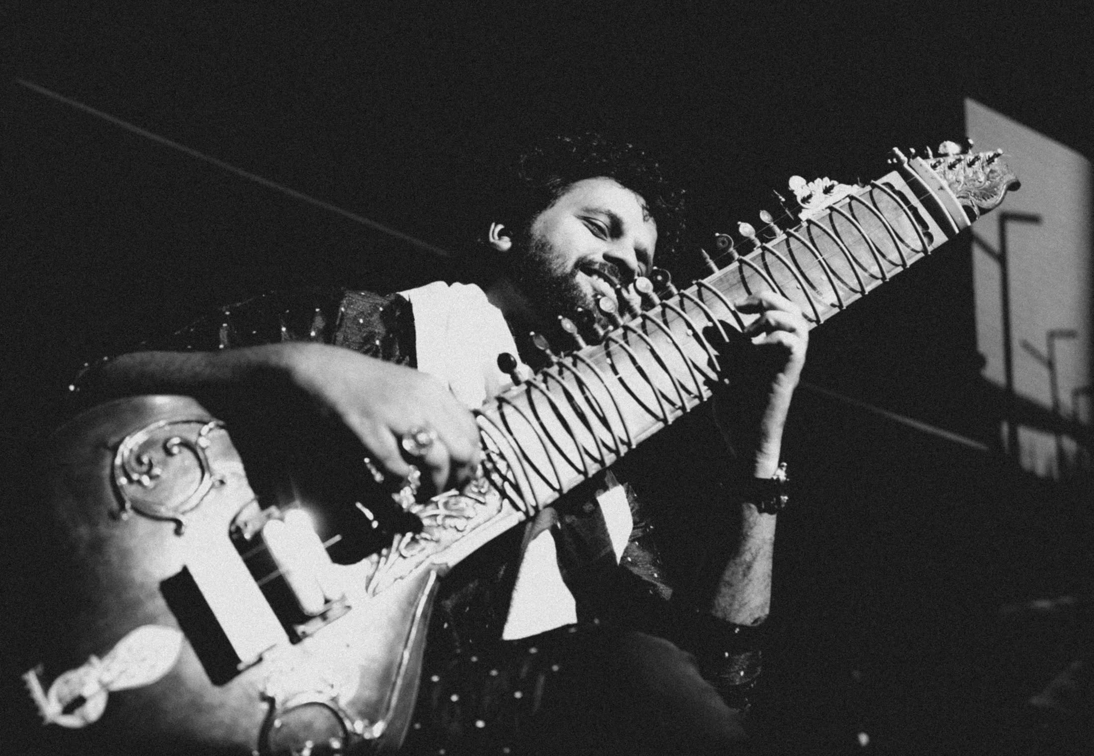 Sitarist leaning into the instrument, in black and white